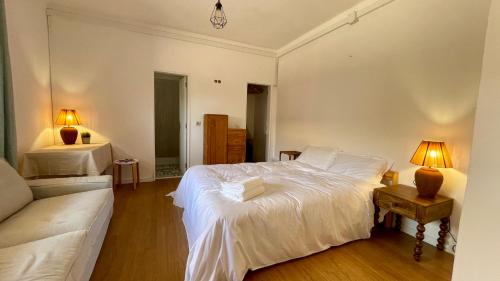 a bedroom with a white bed and a couch at Wild Souls Guesthouse in Ericeira