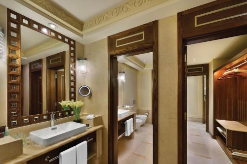 a bathroom with two sinks and two mirrors at Al Bustan Palace, a Ritz-Carlton Hotel in Muscat