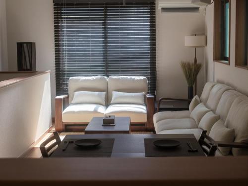 ein Wohnzimmer mit zwei weißen Stühlen und einem Sofa in der Unterkunft GOHO STAY me Sumiyoshi in Tokio