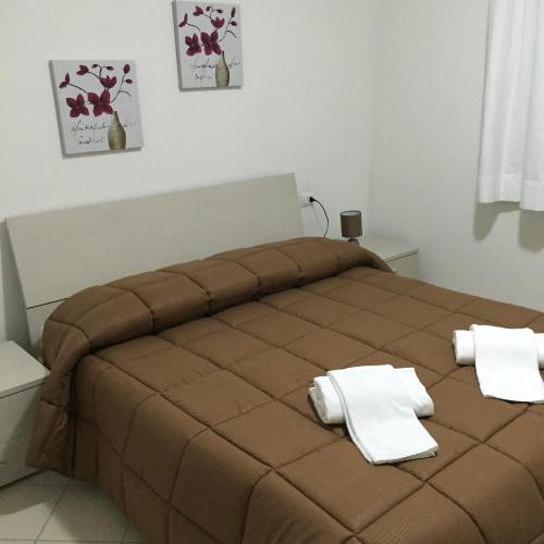 a bedroom with a brown bed with white towels on it at Guest House Suite in Olbia