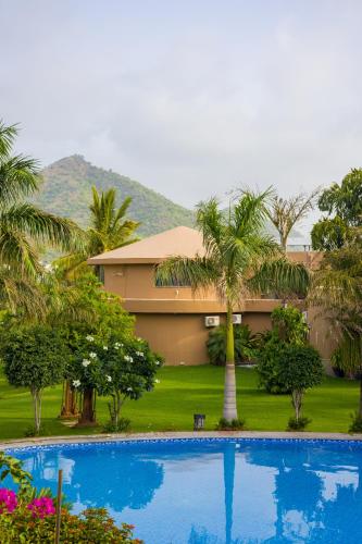 a house with a palm tree and a swimming pool at Alaya Stays Jeevantara by ELIVAAS in Udaipur