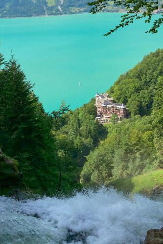 a house on a hill next to a body of water at Brienzersee - Direct lake view in Brienz