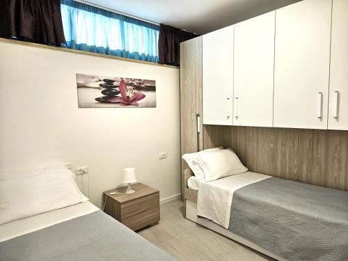 two beds in a small room with white cabinets at I SUONI DEL MARE in Porto San Giorgio
