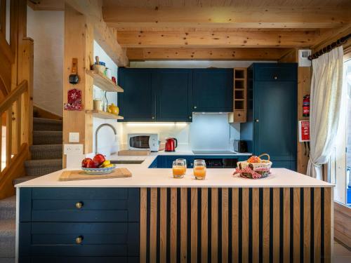 une cuisine avec des placards bleus et un comptoir avec des fruits. dans l'établissement Chalet L'Ours Blanc - OVO Network, au Grand-Bornand