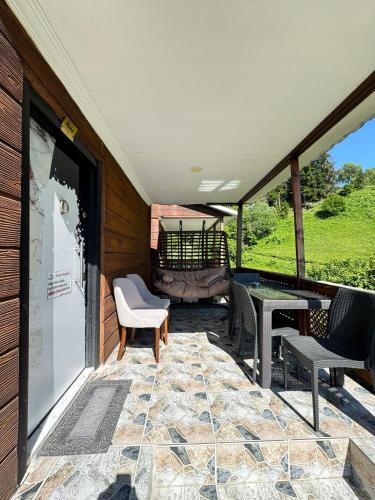 a screened in porch with chairs and a table at Danzot Tatil Köyü ve Restoran in Artvin