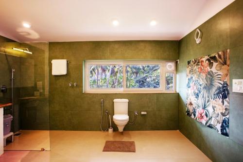 a bathroom with a toilet and a window at Siv Vilas in Old Goa