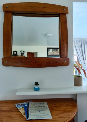 a mirror on top of a table with a book at Sand Sittie in Sandbaai