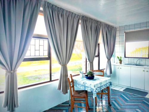 a kitchen with a table and two chairs and windows at Sand Sittie in Sandbaai