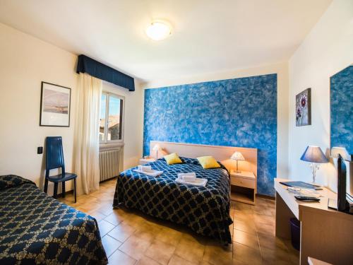 a bedroom with two beds and a desk and a tv at Albergo Centrale in San Zeno di Montagna