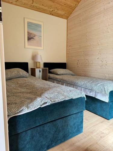 two beds in a room with wooden walls at NOVA domki Cetniewo in Władysławowo