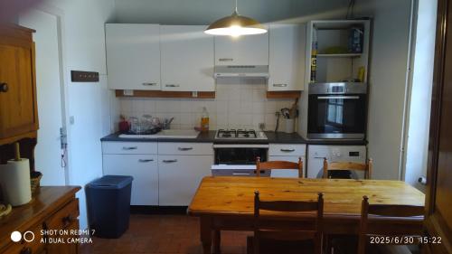 Una cocina con gabinetes blancos y una mesa de madera. en Maison de maître, en Sabres