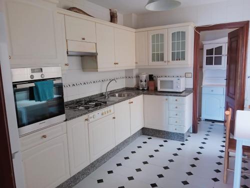 una cucina con armadi bianchi e pavimento in bianco e nero di Apartamento en Cee a Cee