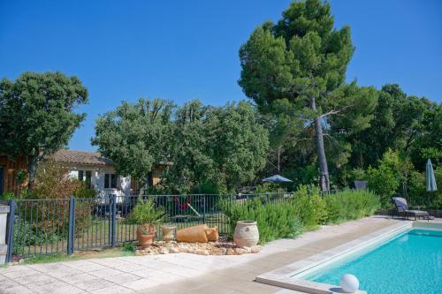 a swimming pool in a yard with a fence at L'écrin de la Garrigue in Saint-Siffret