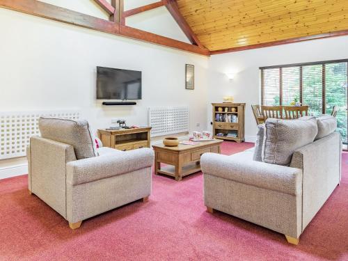 a living room with two chairs and a tv at Cedar Barn - Ukc5406 in Banham