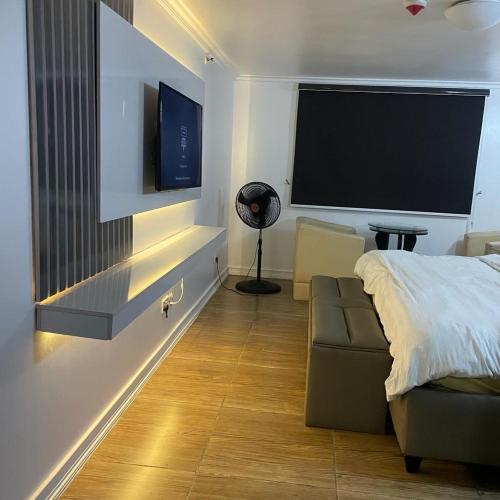 MamaにあるGolden tulip apartmentのベッド、ソファ、薄型テレビのある寝室