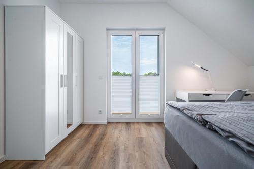 a white bedroom with a bed and a window at Seeglück 1 am Tollensesee in Groß Nemerow