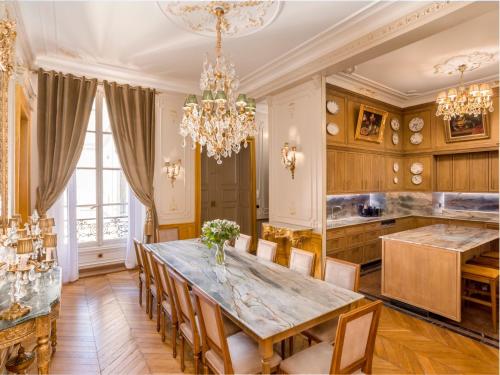 une salle à manger avec une table, des chaises et un lustre dans l'établissement Merveil - Signature Suite - Marais - Braque, à Paris