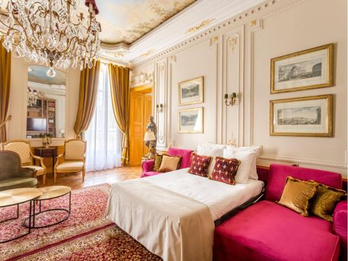 - un salon avec un canapé rose et un lustre dans l'établissement Merveil - Signature Suite - Marais - Braque, à Paris
