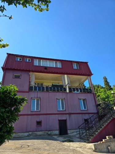 a pink building with a red roof at Guest house EMZAR in Chakvi