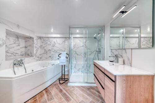 a bathroom with a tub and a sink and a shower at Le Pouteau charme authentique 2 chambres in Lyon