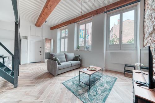 a living room with a couch and a table at Le Pouteau charme authentique 2 chambres in Lyon