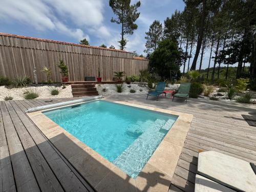 - une piscine dans un jardin avec une terrasse en bois dans l'établissement Villa Les Pins, terrasse, piscine et jardin clôt, vue forêt, à Mimizan