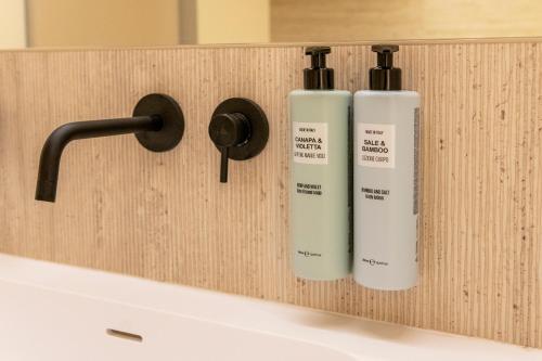two bottles ofodorizers on a wooden wall above a sink at International Hotel & Suite in San Benedetto del Tronto