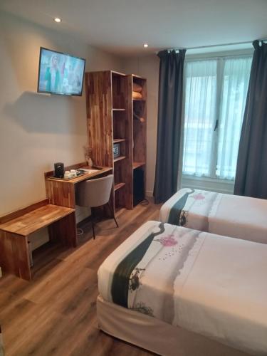 a hotel room with two beds and a desk at Hotel Modern Est in Paris