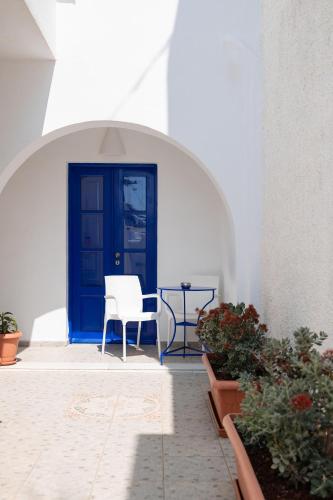 a blue door with a white chair and some plants at Villa Happening in Imerovigli