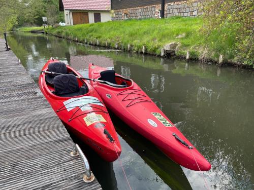 a red kayak sitting on the water next to a dock at Spreewald Pension Spreeaue in Burg