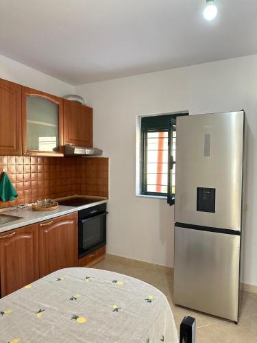 a kitchen with a stainless steel refrigerator and wooden cabinets at Borsh Village Nest in Borsh