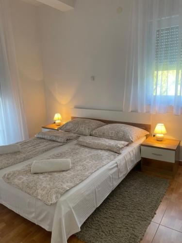 a bedroom with a large bed with two lamps at Apartmani Marković RAB in Palit