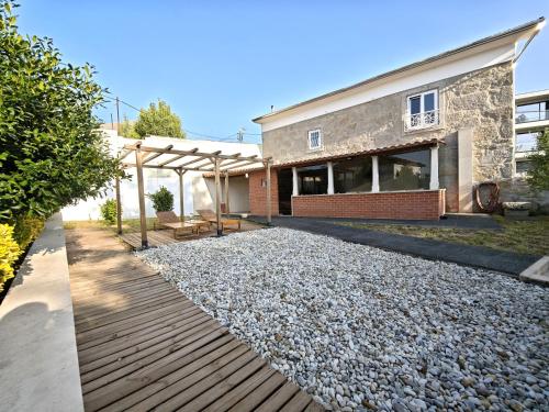 a backyard with a stone house and a wooden walkway at Well at Home in Vila Nova de Gaia