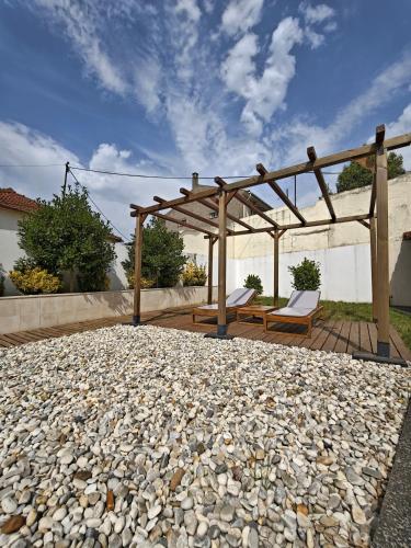 a stone patio with a wooden pergola and two chairs at Well at Home in Vila Nova de Gaia