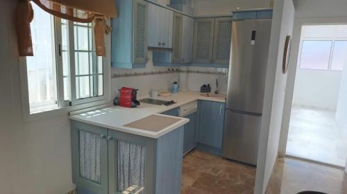 a kitchen with blue cabinets and a sink and a refrigerator at Casa Tuca by 7Escalones in Rota