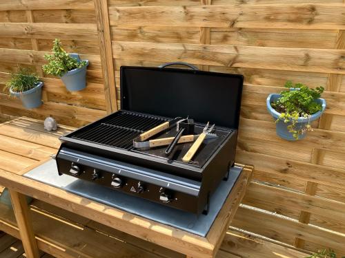 a bbq grill on a table with potted plants at Le Logis des Vallées, 6/7 pers avec piscine et sauna in Ambrieres Les Vallees