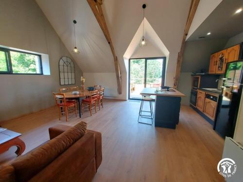 a large living room with a table and a kitchen at Le Logis des Vallées, 6/7 pers avec piscine et sauna in Ambrieres Les Vallees