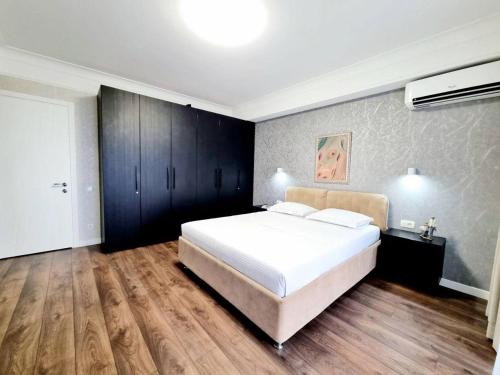 a bedroom with a large white bed and wooden floors at The Central Collection Apartments in Chişinău
