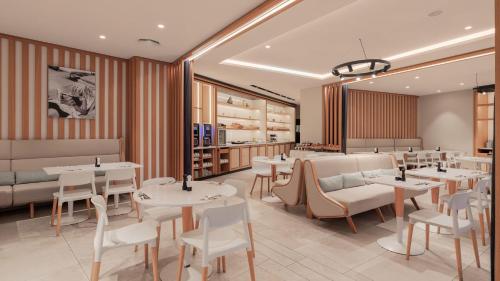 Un restaurante con mesas y sillas blancas y buscador de mesas en Holiday Inn Nice - Port St Laurent by IHG, en Saint-Laurent-du-Var