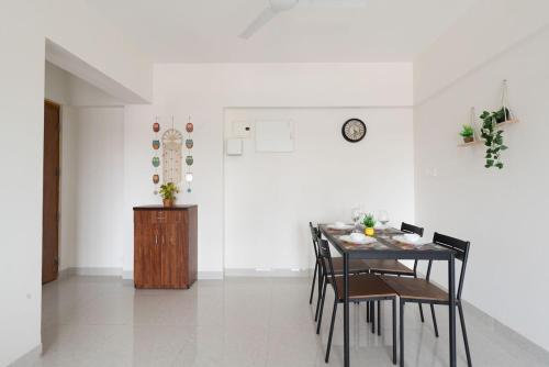 une salle à manger avec une table, des chaises et une horloge dans l'établissement Boho, Breezy, Sun-Kissed 2bhk nr BKC & Airport, à Mumbai