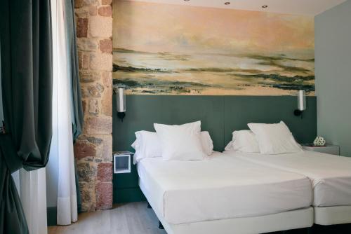 a bedroom with a bed with a painting on the wall at Hotel Balneario La Hermida in La Hermida