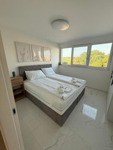 a bedroom with a large bed and two windows at Apartmen ARMINAN 52 TERRACE, POOL FREE PARKING -NOVIGRAD in Novigrad Istria