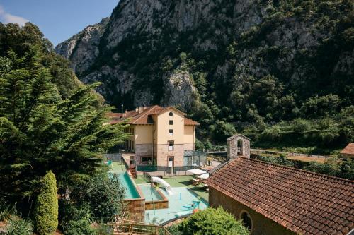 a resort with a swimming pool in front of a mountain at Hotel Balneario La Hermida in La Hermida