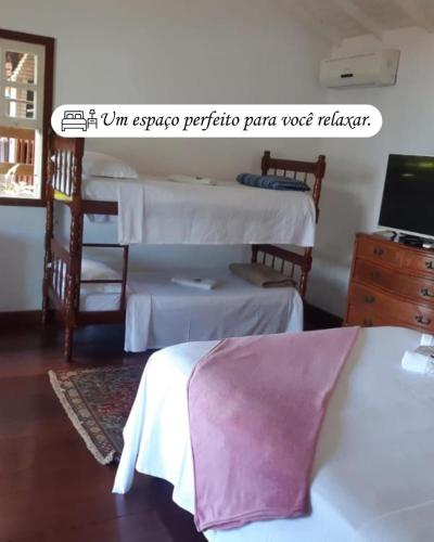 a room with two beds and a desk with a computer at Pousada Éden in Angra dos Reis
