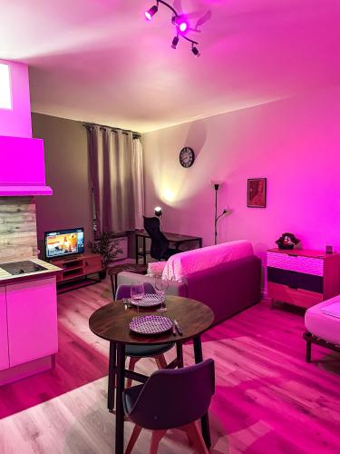 un salon avec un éclairage rose et une table dans l'établissement Escapade Ardéchoise - Parking Gratuit - Château à 2 pas, à Aubenas