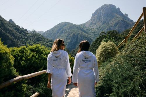 two women walking down a wooden walkway looking at the mountains at Hotel Balneario La Hermida in La Hermida