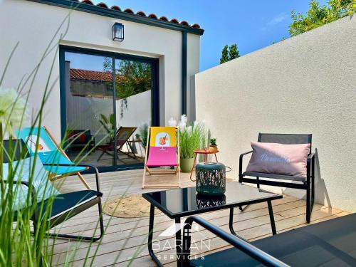 a patio with chairs and a table on a deck at La Maévague - Villa 4 étoiles - Voyage entre mer et monde in Fouras