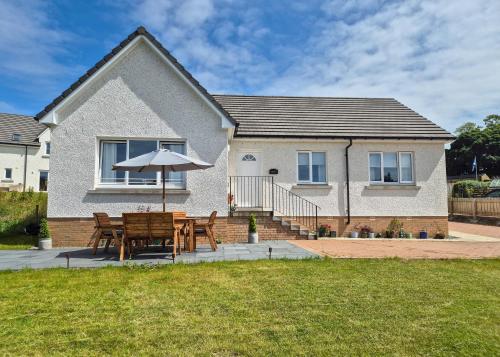 a table and an umbrella in front of a house at Kilin in Lochgilphead