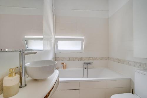 une salle de bain blanche avec une baignoire et un lavabo dans l'établissement Appartement Romantique à Saint-Ouen, à Saint-Ouen