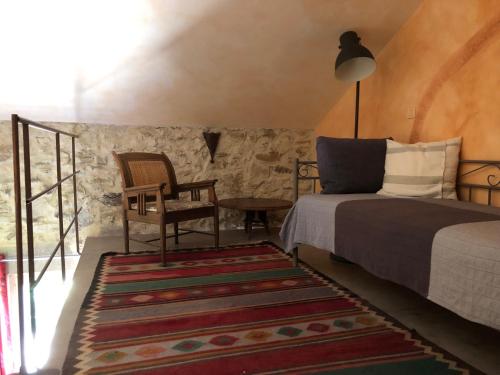 une chambre avec un lit, une chaise et un tapis dans l'établissement mas de costebelle, à Bollène